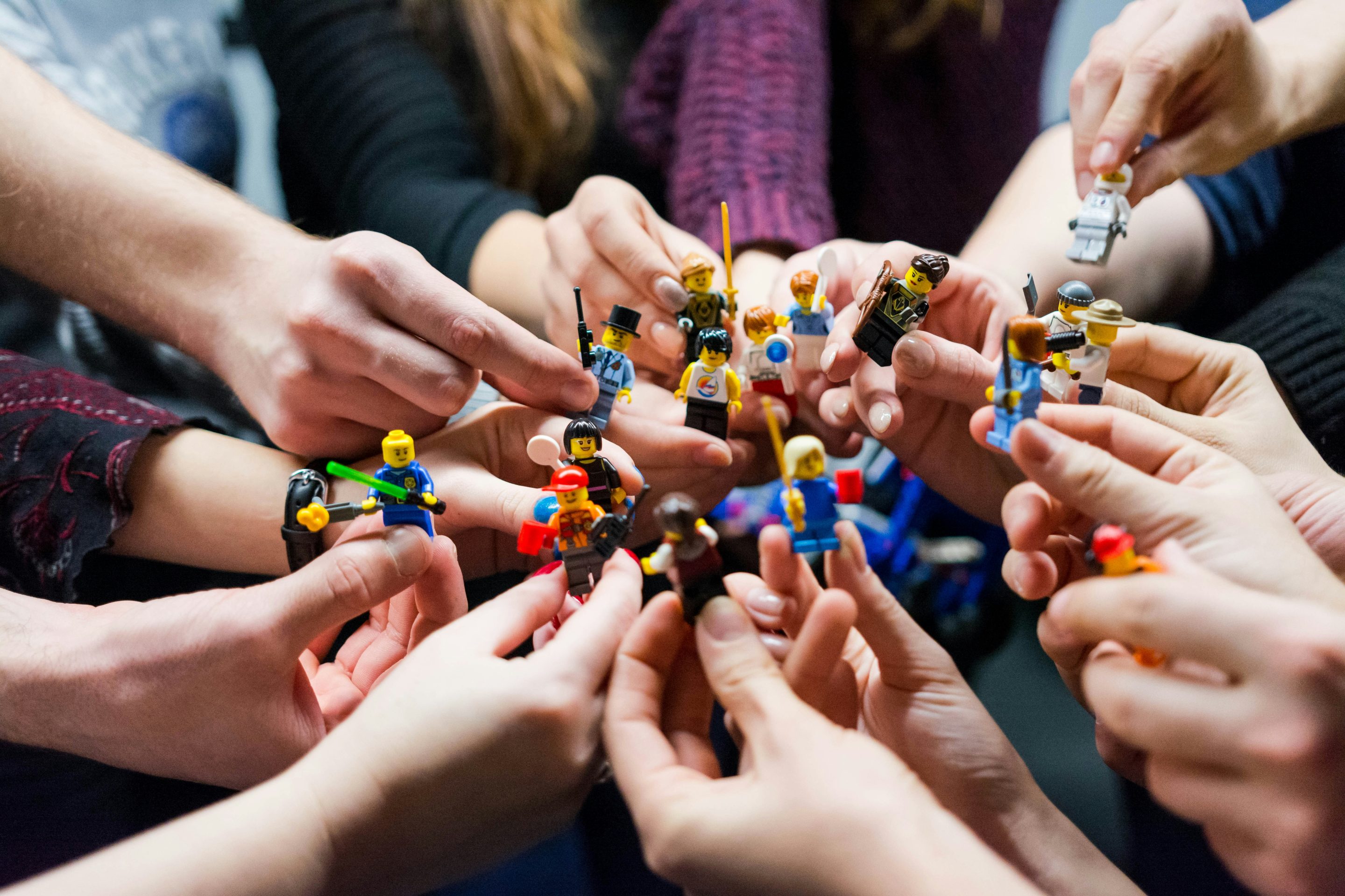 A Group Holding Colourful Toy Figures Together In A Circle